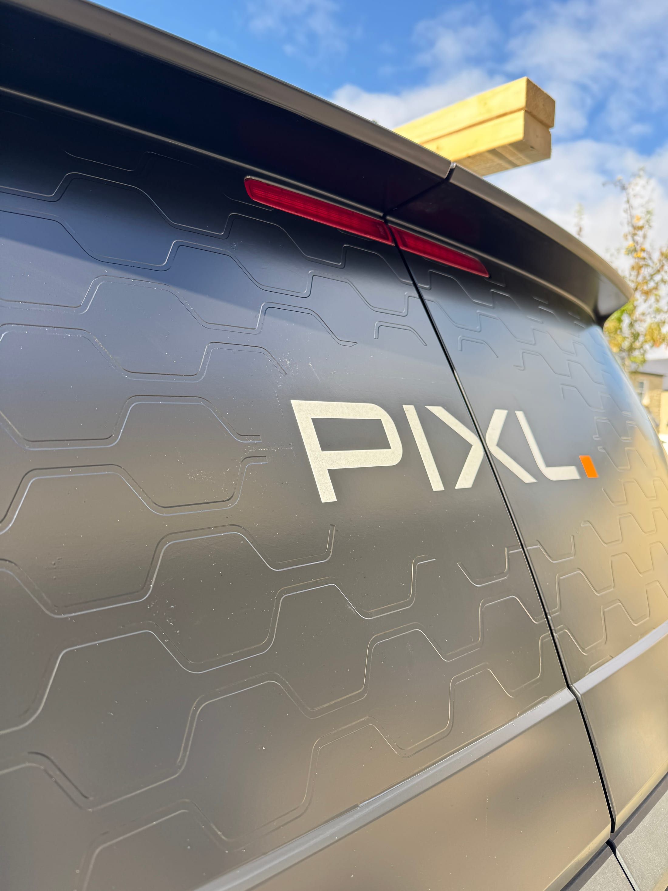 Close-up of the PIXL logo applied to a dark vehicle rear panel.